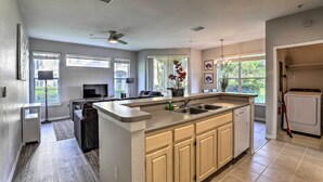Una cocina moderna con una isla central, electrodomésticos integrados y ventanas amplias.