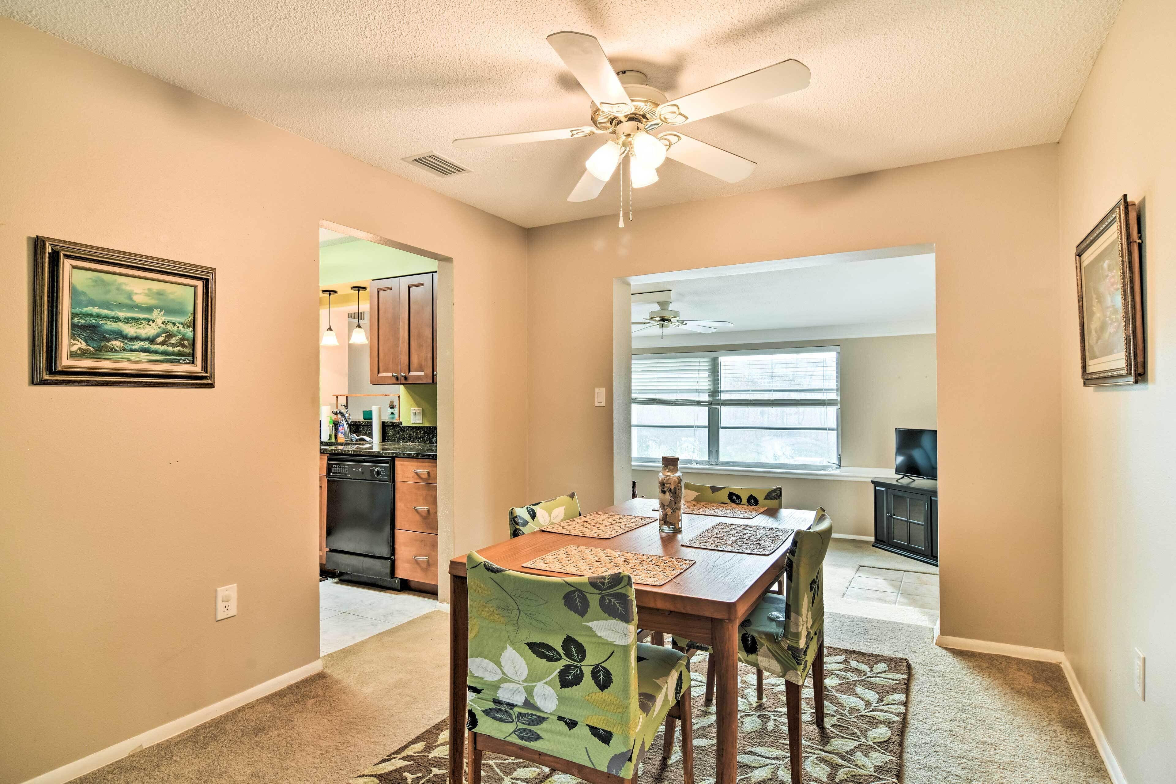A dining area with a wooden table, chairs, and a ceiling fan.