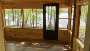 Una baita con interni in legno, ampie finestre e vista su un lago.