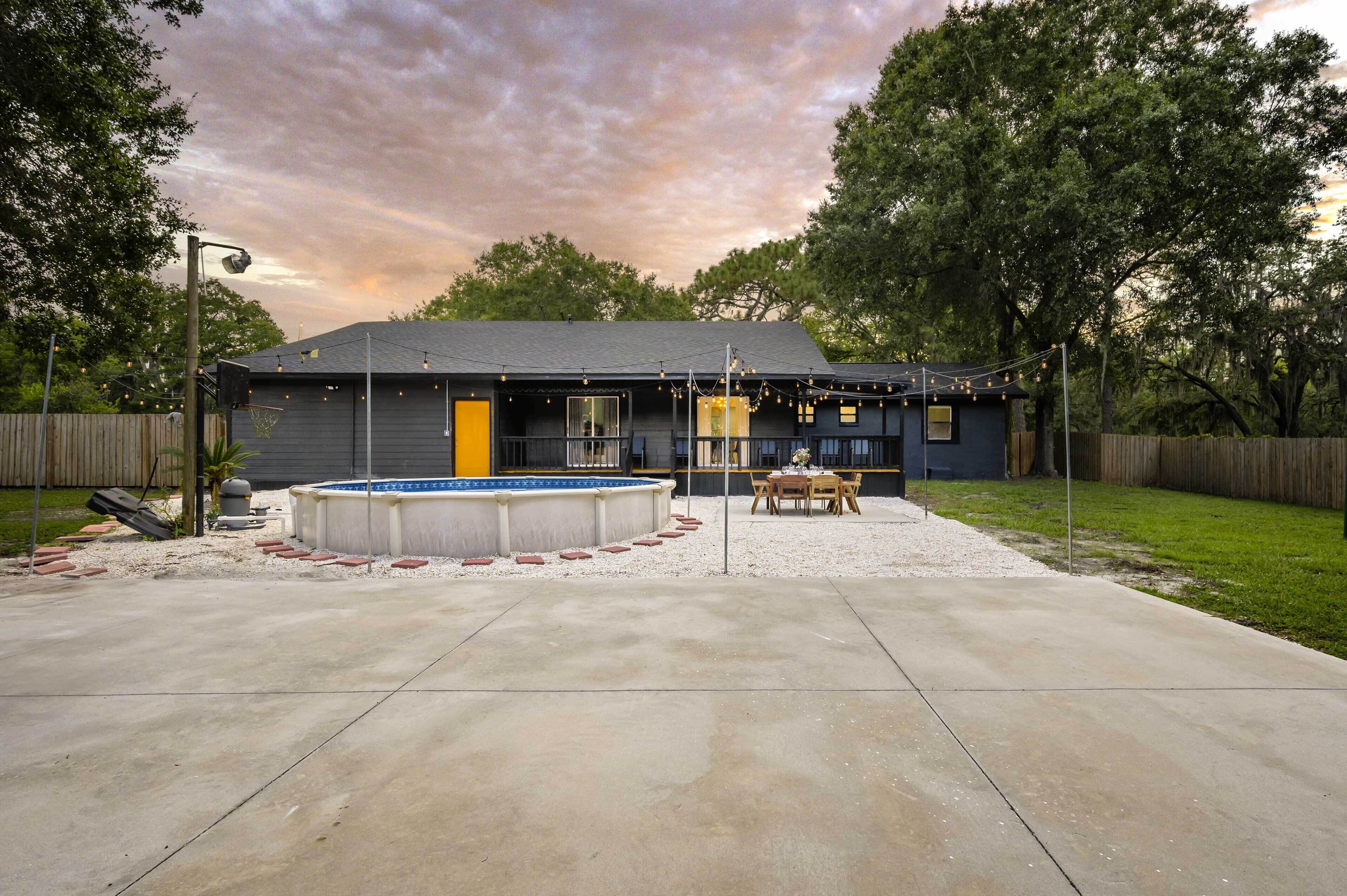 Une maison dotée d’une cour arrière comprenant une terrasse en béton, une petite piscine et une plateforme en bois.