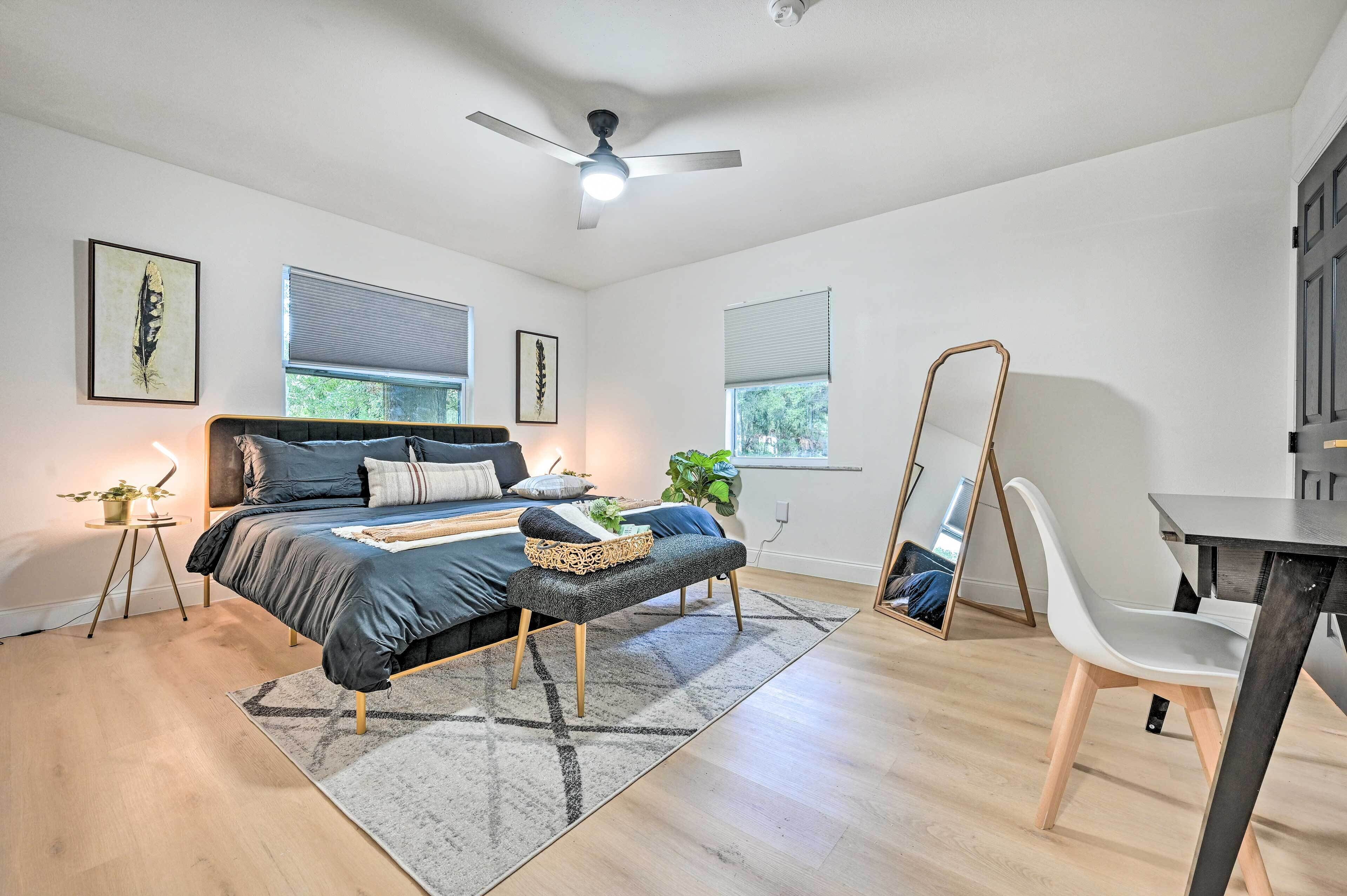 Ein modernes Schlafzimmer mit Bett, Nachttischen, einem Stehspiegel und einem Schreibtisch.