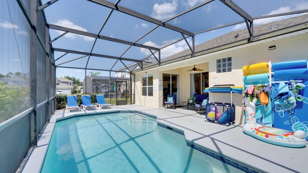 An indoor swimming pool with clear blue water, surrounded by lounge chairs and a poolside area with a covered patio. - Pool, Themed Rooms & Arcade: Disney Escape (Kissimmee)