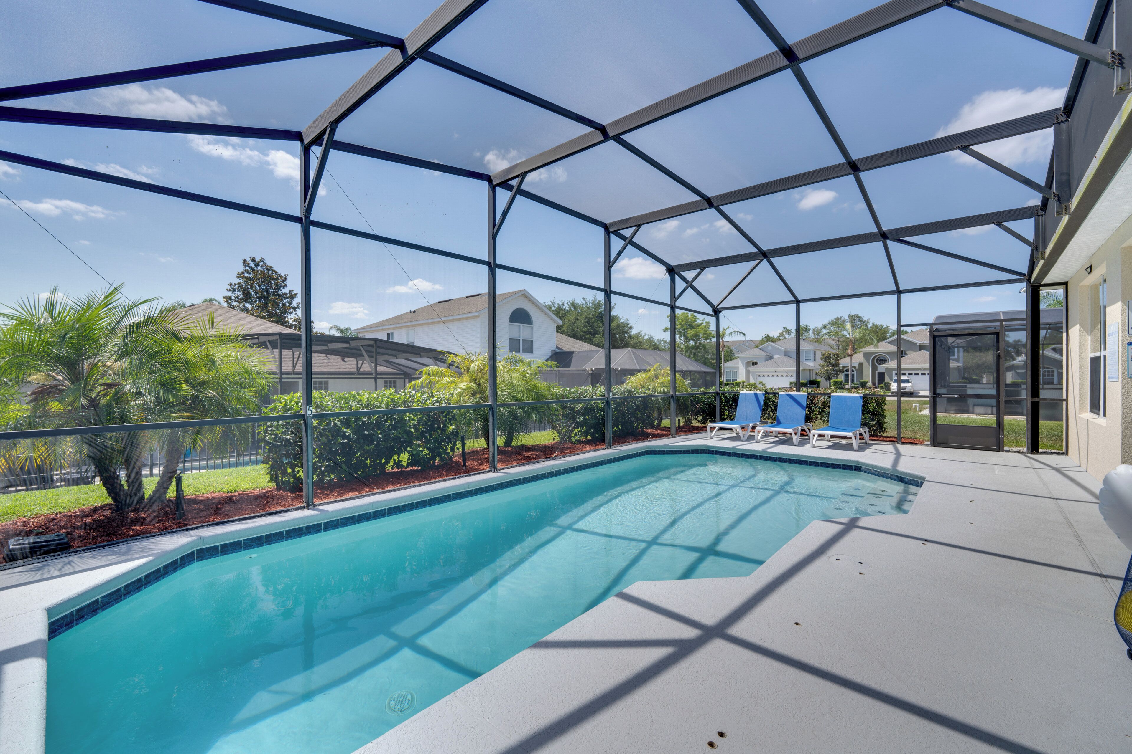 Una piscina techada con vistas despejadas del vecindario circundante, incluyendo casas y árboles.