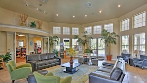 A spacious lobby with a leather sofa, green armchairs, a coffee table, and a large window overlooking the outdoors. - Pool, Themed Rooms & Arcade: Disney Escape (Kissimmee)