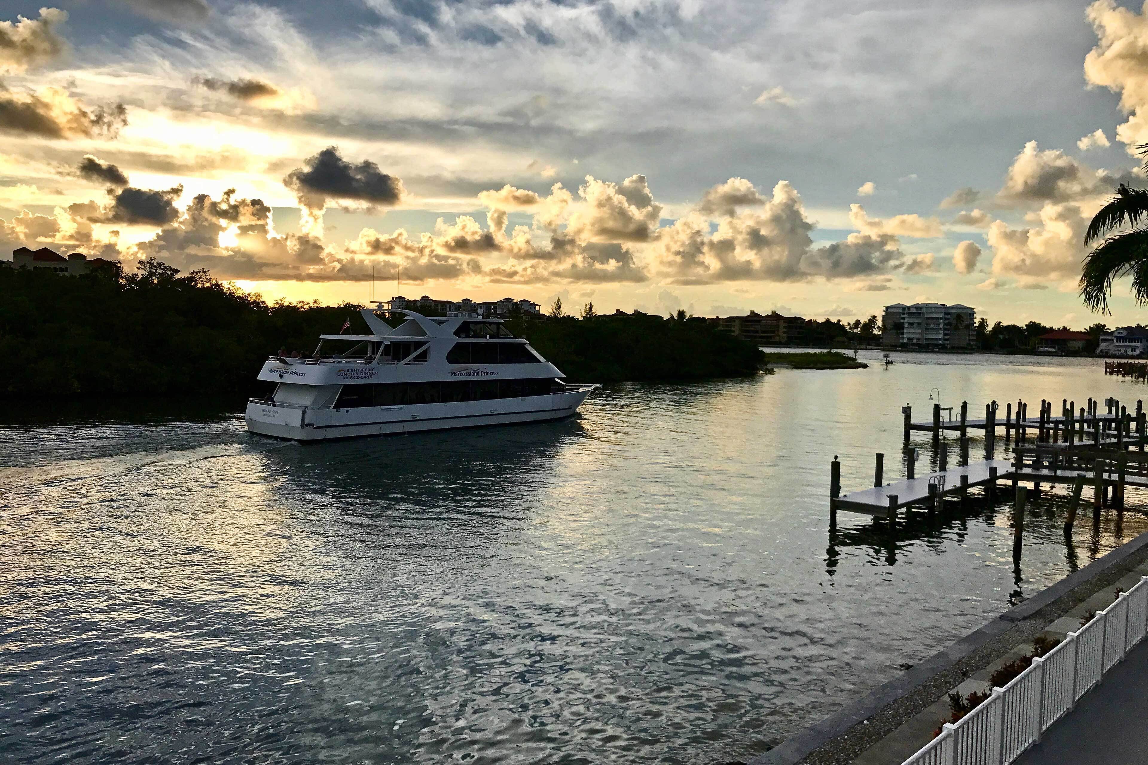 Un yate blanco amarrado en un puerto deportivo, con muelle y paseo peatonal.