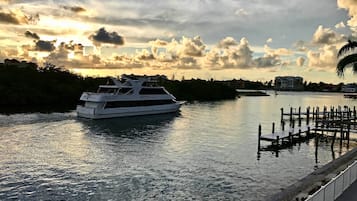 Un yate blanco amarrado en un puerto deportivo, con muelle y paseo peatonal.
