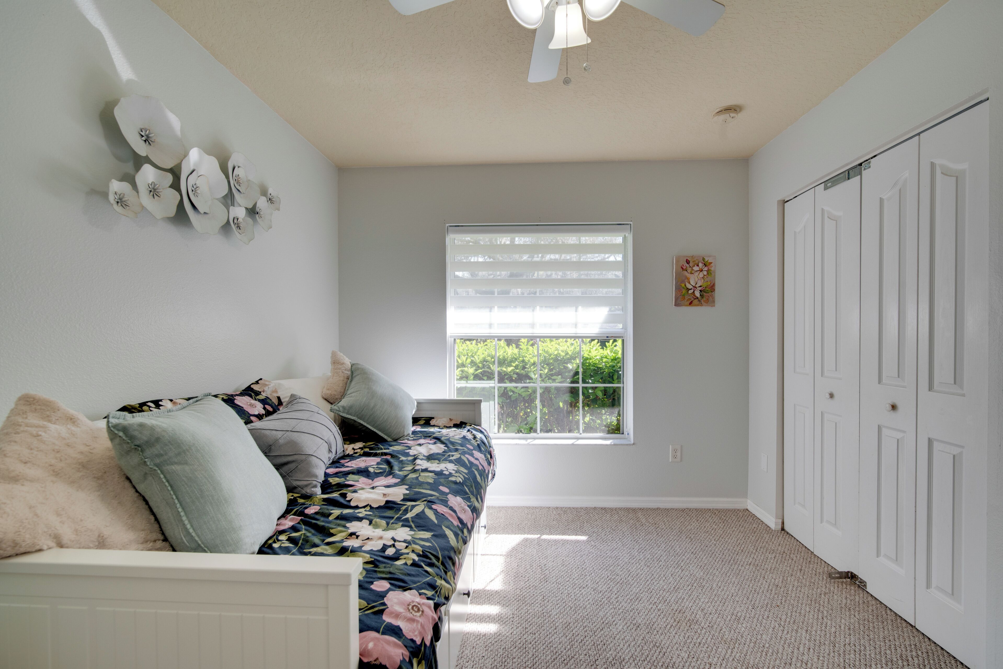 A bedroom with a bed, a window with blinds, a ceiling fan, and a closet.