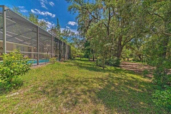A modern building with a glass facade, surrounded by lush greenery and trees.