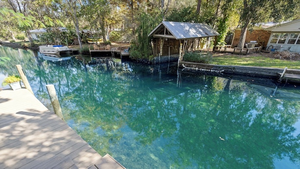 A clear water body with a wooden dock, a small wooden structure, and a house in the background. - Decks, Docks & Kayaks: Waterfront Homosassa Gem (Homosassa)