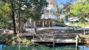 A two-story building with a balcony, a wooden deck, and a clear water body in front. - Decks, Docks & Kayaks: Waterfront Homosassa Gem (Homosassa)