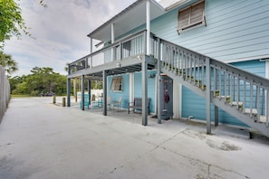 A covered outdoor area with a staircase leading to a second floor, outdoor seating, and a vehicle parked nearby. - PCB Group Retreat w/ Deck, 1 Block to Beach! (Panama City Beach)