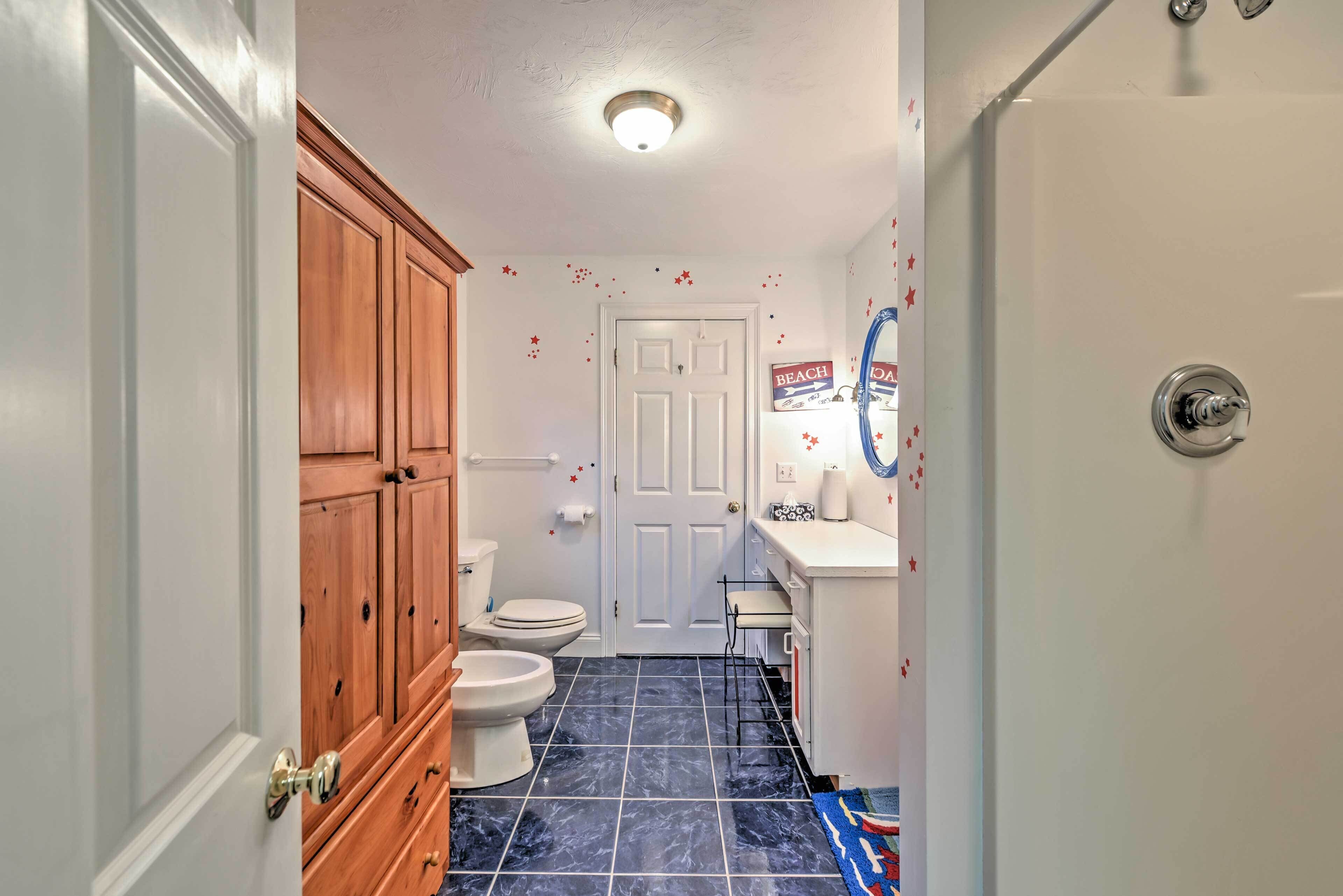 A bathroom with wooden cabinets, a white toilet, a sink with a mirror, and a blue tiled floor.
