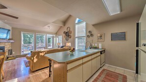Une cuisine spacieuse dotée d’un grand îlot central, d’un plancher en bois et offrant une vue sur l’extérieur.