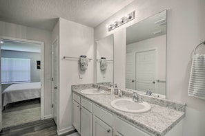 A bathroom with two sinks, a large mirror, and a towel rack.