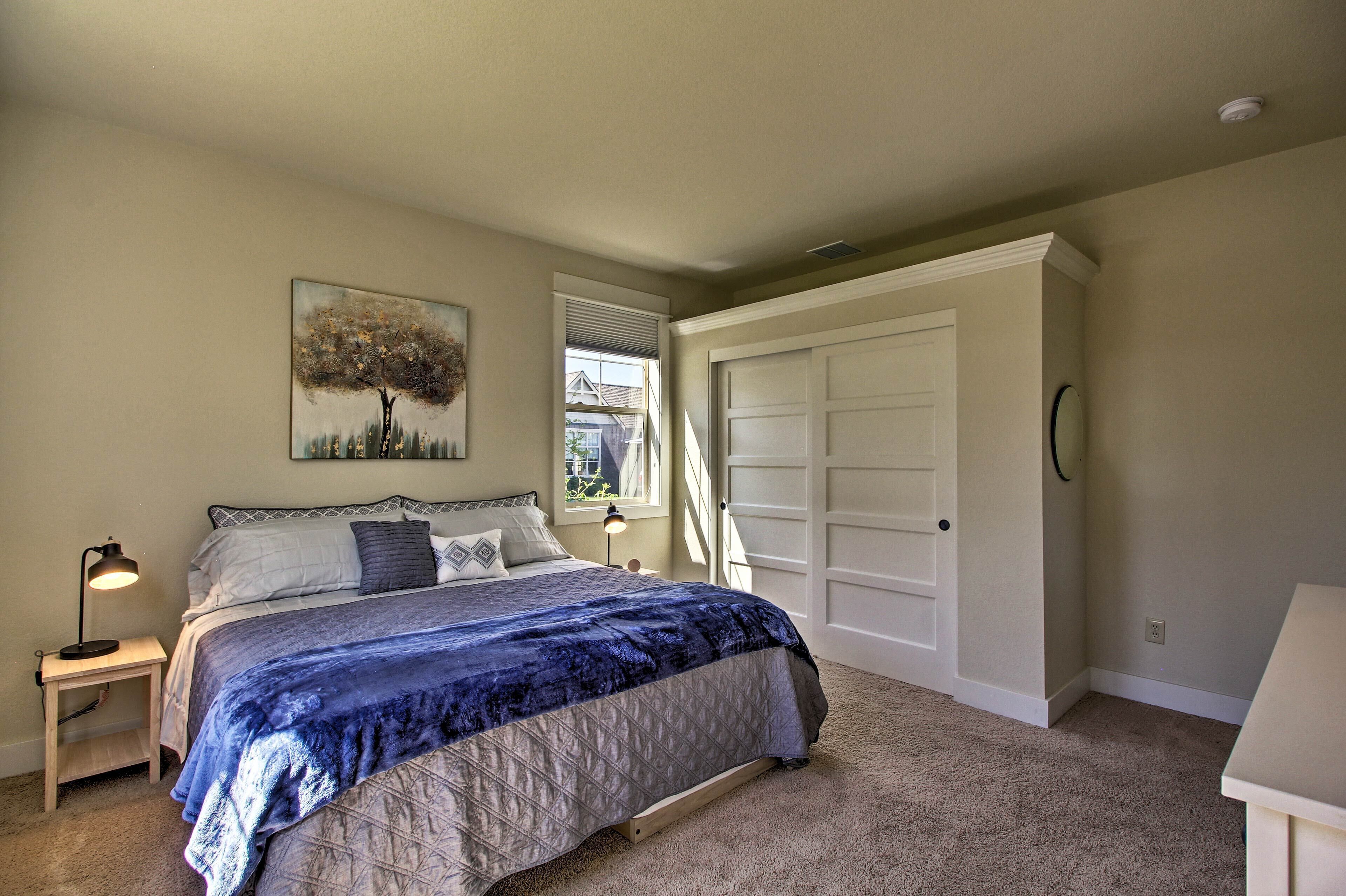 A bedroom with a bed, a nightstand, a window, and a closet.