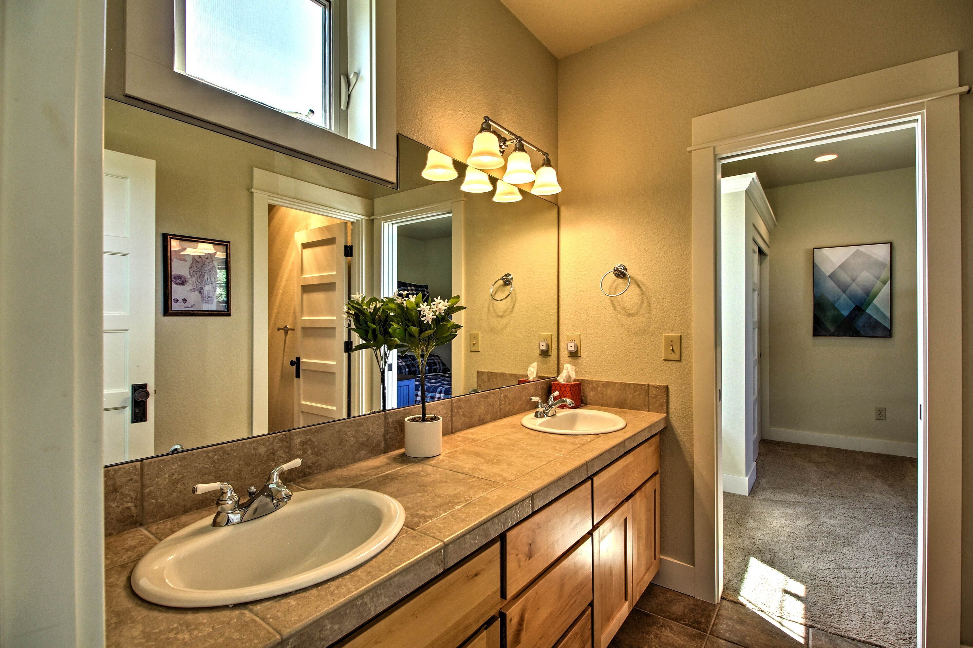A bathroom with a double sink, a large mirror, and a light fixture above the mirror.