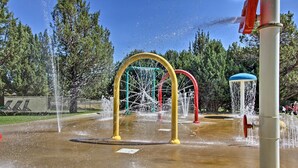 A water play area with multiple water jets and a playground structure. - Redmond House w/ Community Amenities Access (Redmond)