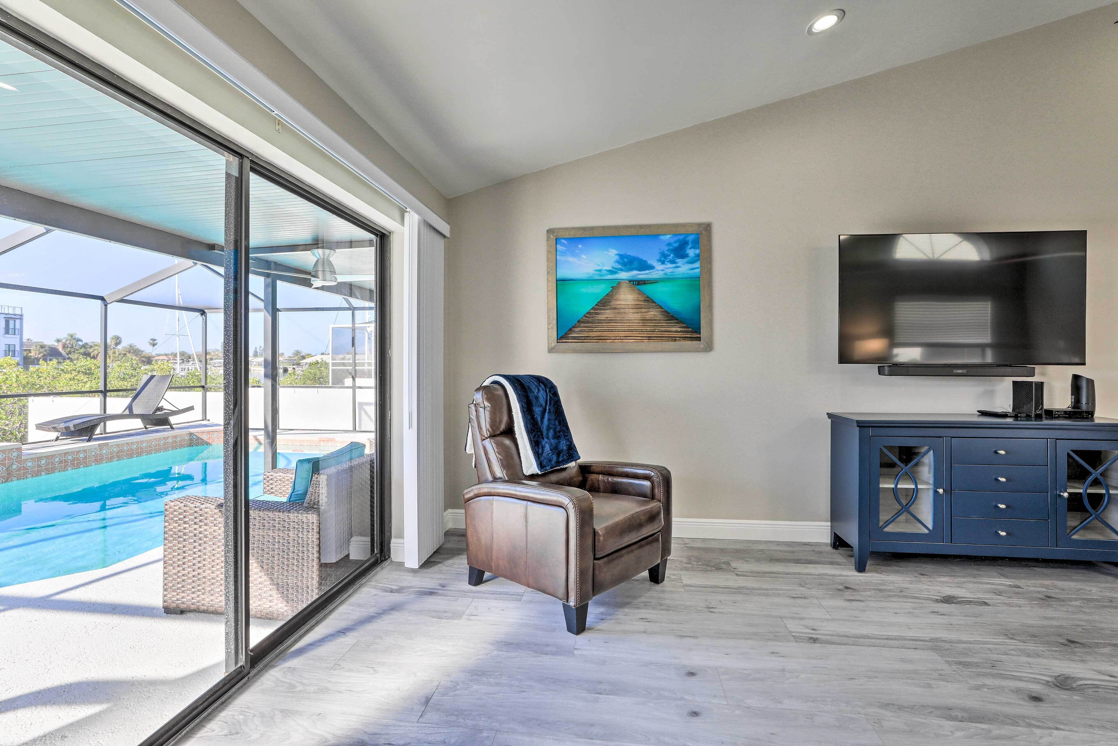 A modern living room with a leather chair, a TV, and a view of a pool.