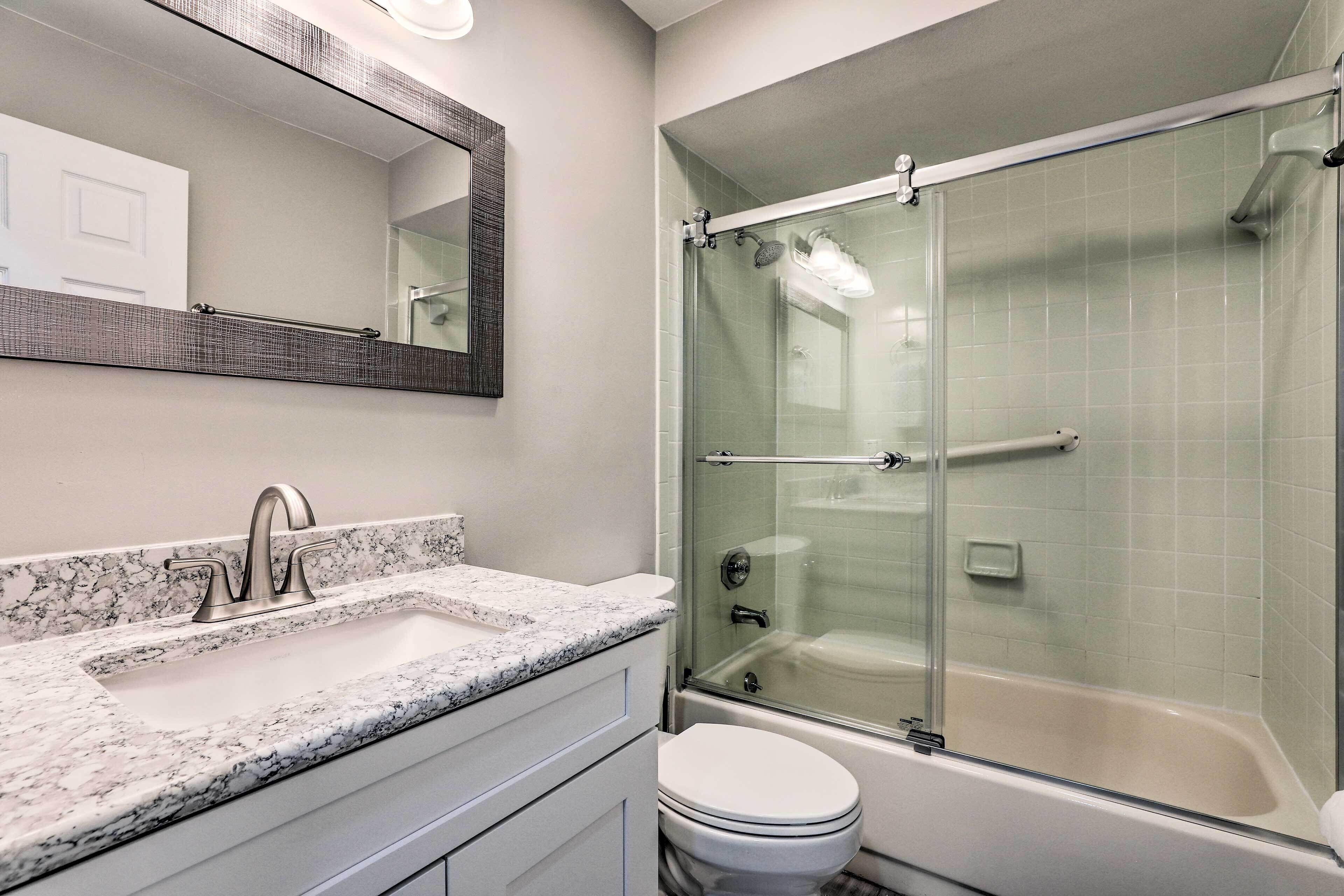 Une salle de bain avec une douche à parois de verre, un lavabo doté d’un plan de toilette en marbre et des toilettes.
