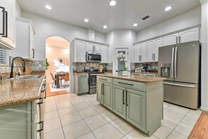 A spacious kitchen with light green cabinets, stainless steel appliances, and a granite countertop. - Thonotosassa Villa: Pool, Spa & Game Room (Thonotosassa)