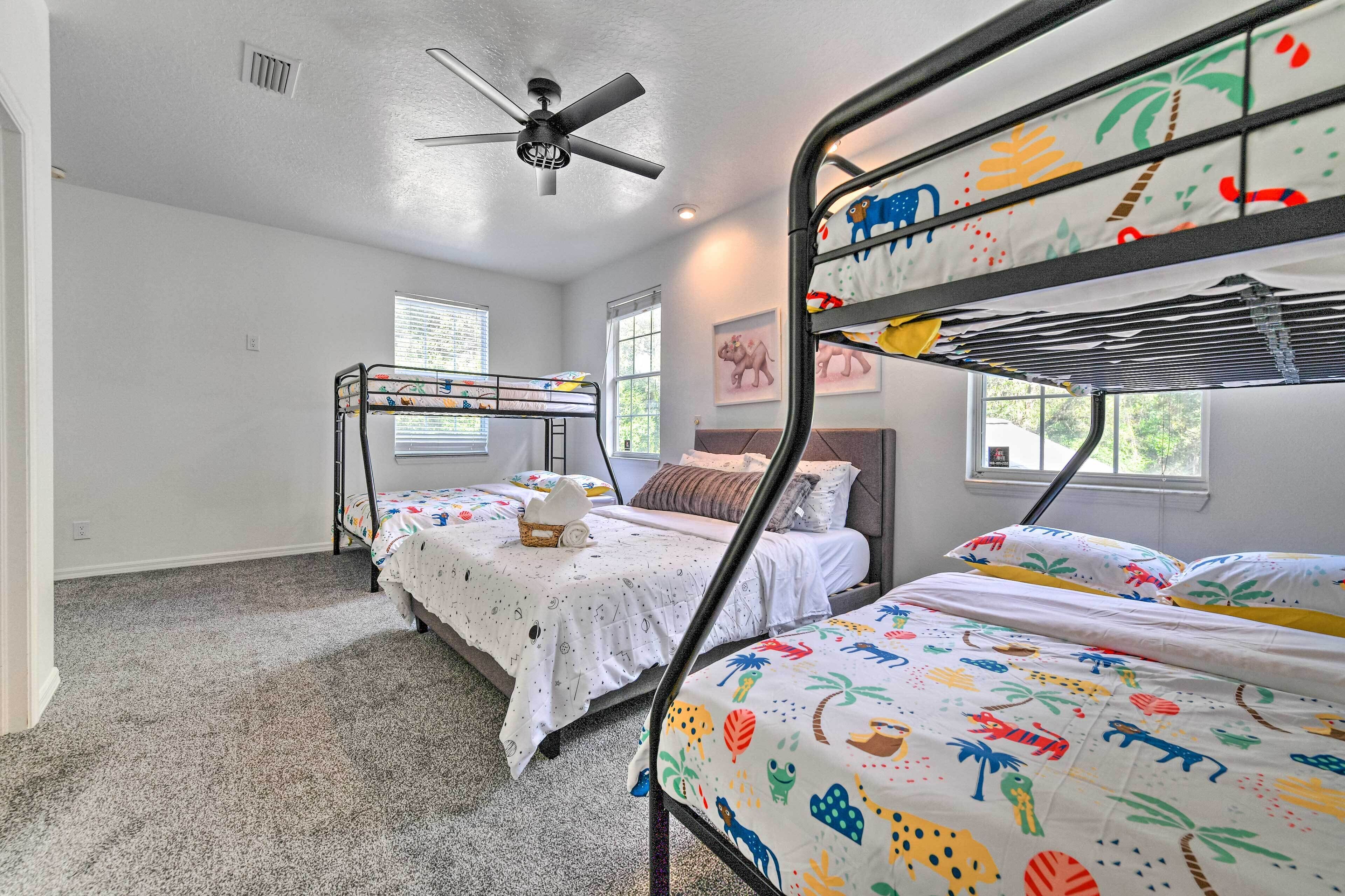 A room with bunk beds, a ceiling fan, and a window with blinds.
