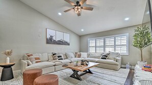 Ein Wohnzimmer mit Ecksofa, Couchtisch und Deckenventilator.