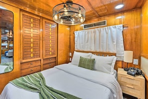 Un dormitorio con paneles de madera, una cama grande, una mesita de noche, un teléfono y un espejo.