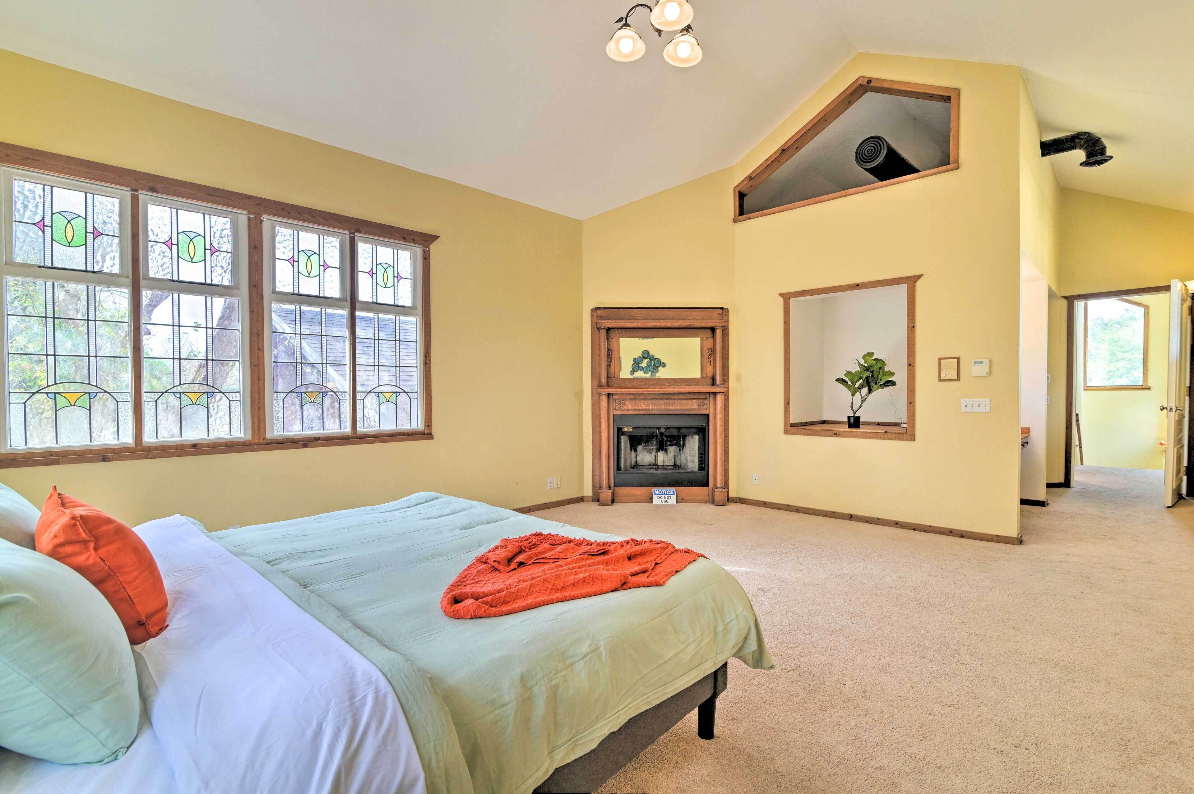 Een slaapkamer met een bed, een open haard en een raam met glas-in-lood.