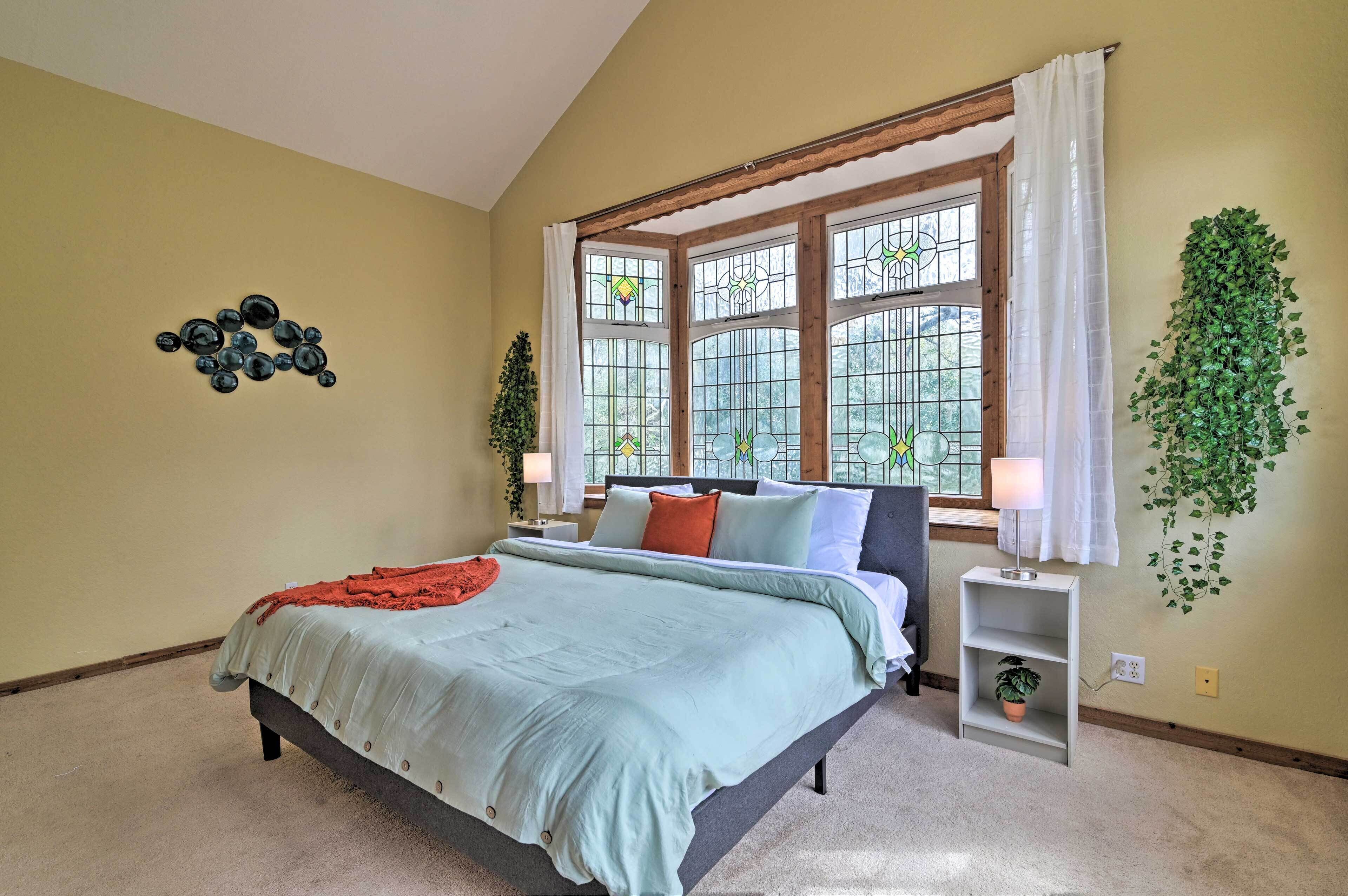 A bedroom with a bed, a nightstand, a window with curtains, a wall-mounted plant, and a wall decoration.