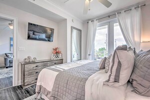 Un dormitorio con cama, cómoda, televisor y ventana con cortinas.