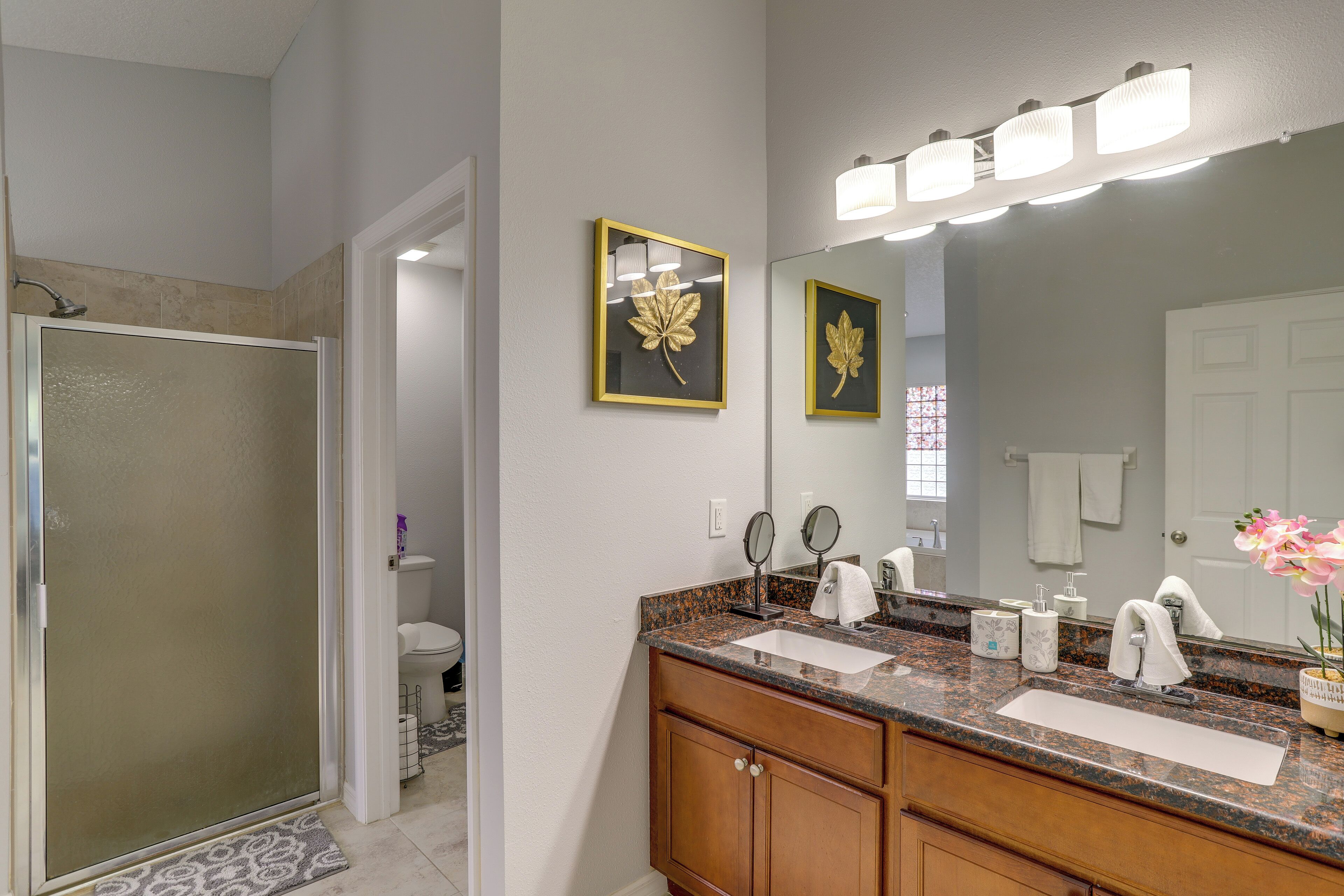A bathroom with a shower, two sinks, a vanity, and a large mirror.