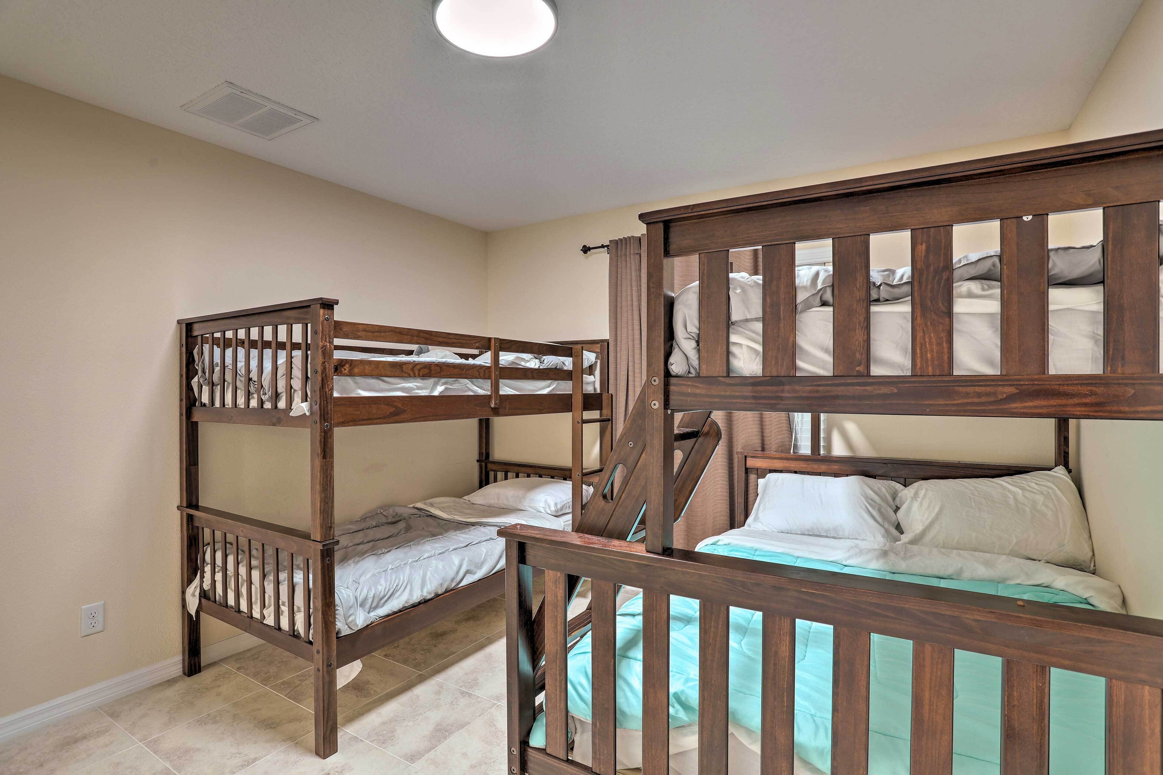 A room with bunk beds, a ceiling light, and a plain wall.