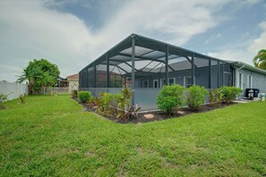 A house with a large covered porch, a fenced yard, and a variety of plants.