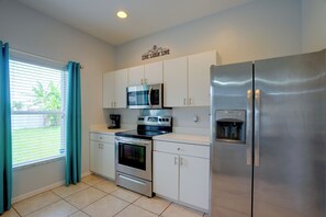 A modern kitchen with stainless steel appliances, including a refrigerator, oven, and microwave, and white cabinetry.