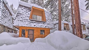 Eine Holzhütte mit schneebedecktem Dach und einem kleinen Fenster.