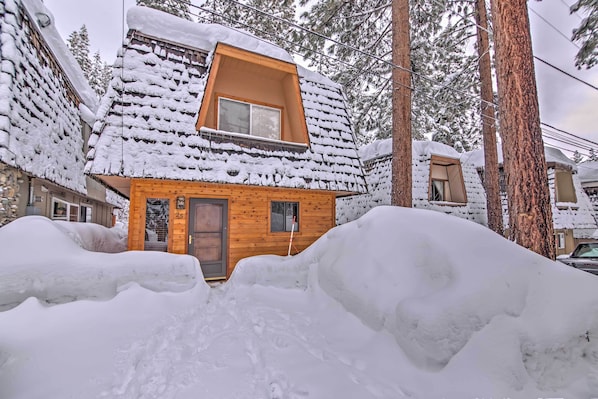 Une cabane en bois avec un toit enneigé et une petite fenêtre.