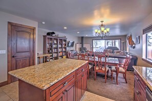 A spacious kitchen with granite countertops, wooden cabinetry, and a dining area with a large table and chairs.