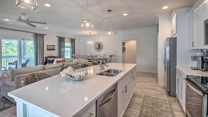 Una cucina moderna con un'ampia isola, elettrodomestici in acciaio inossidabile e illuminazione a sospensione.