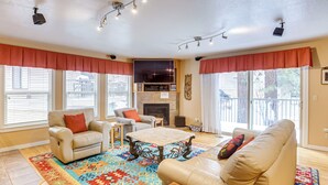 Ein geräumiges Wohnzimmer mit Kamin, Ledersofas und einem großen Fernseher.