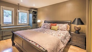 Ein Schlafzimmer mit Bett, Nachttischen, einer Lampe, einem Fenster und einer eingebauten Schrankwand.