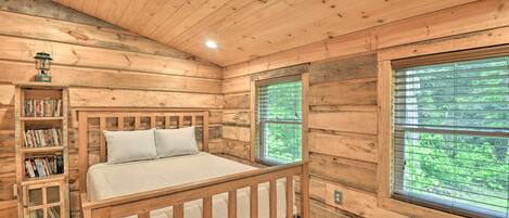 Un dormitorio de cabaña de madera con una cama, una estantería y una ventana con persianas.
