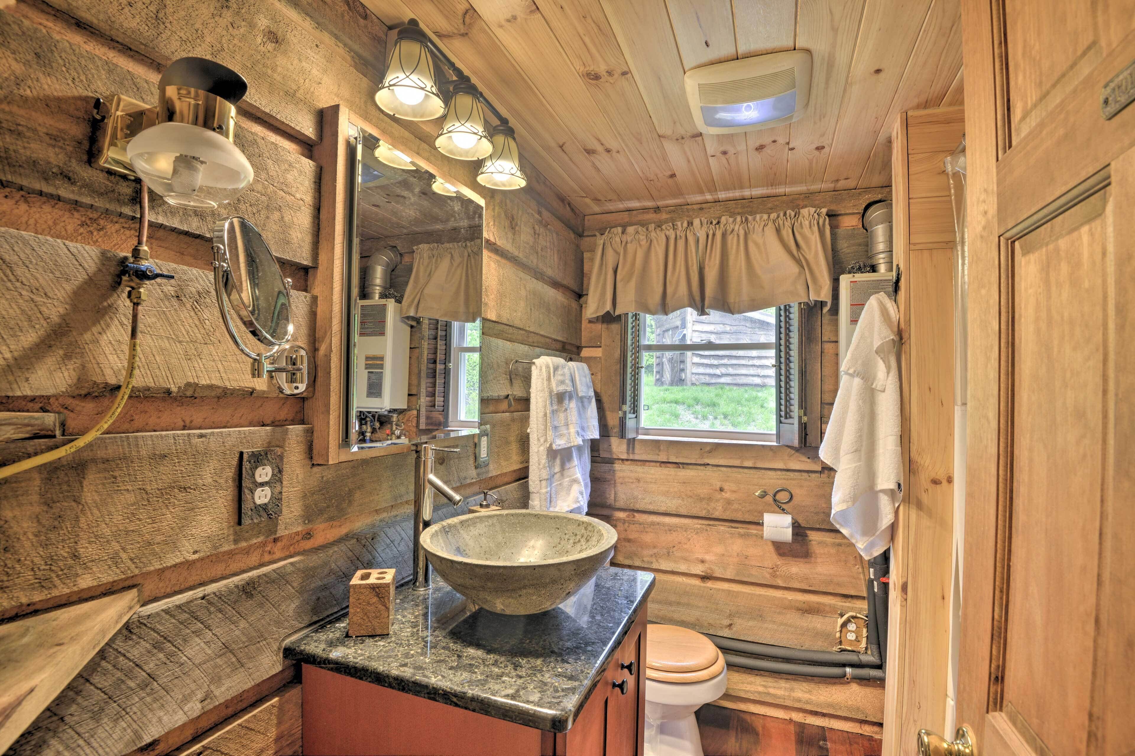 Un baño rústico de madera con un lavabo grande tipo cuenco, un espejo y una ventana con cortinas.