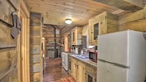 Een houten cabin met een keukenhoek, inclusief een koelkast, fornuis, spoelbak en magnetron.