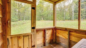 Une cabane en bois dotée de grandes fenêtres donnant sur une zone boisée.