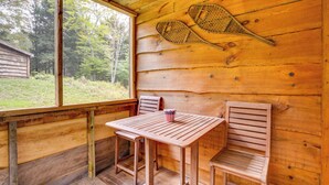 Une cabane en bois avec une table et deux chaises, une raquette de tennis et un petit drapeau américain décoratif.
