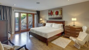 A hotel room with a large bed, a wooden dresser, a chair, and a painting on the wall. - Dtwn Palm Springs Condo: Bbq, Pool, Fire Pit, Etc! (Palm Springs)