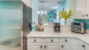 A kitchen with white cabinets, a stainless steel refrigerator, a coffee station, and a toaster. - Fall Retreat at Barefoot Resort 1st Floor (North Myrtle Beach)