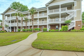 A multi-story residential building with balconies, a central walkway, and a brick facade.