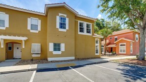 A yellow building with white shutters, a parking lot, and a tree. - Townhome in Berkeley Lake Resort, 9 Mi to Wdw! (Kissimmee)