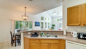 A kitchen with wooden cabinets, a dishwasher, a sink, and a window with a view of greenery. - Townhome in Berkeley Lake Resort, 9 Mi to Wdw! (Kissimmee)